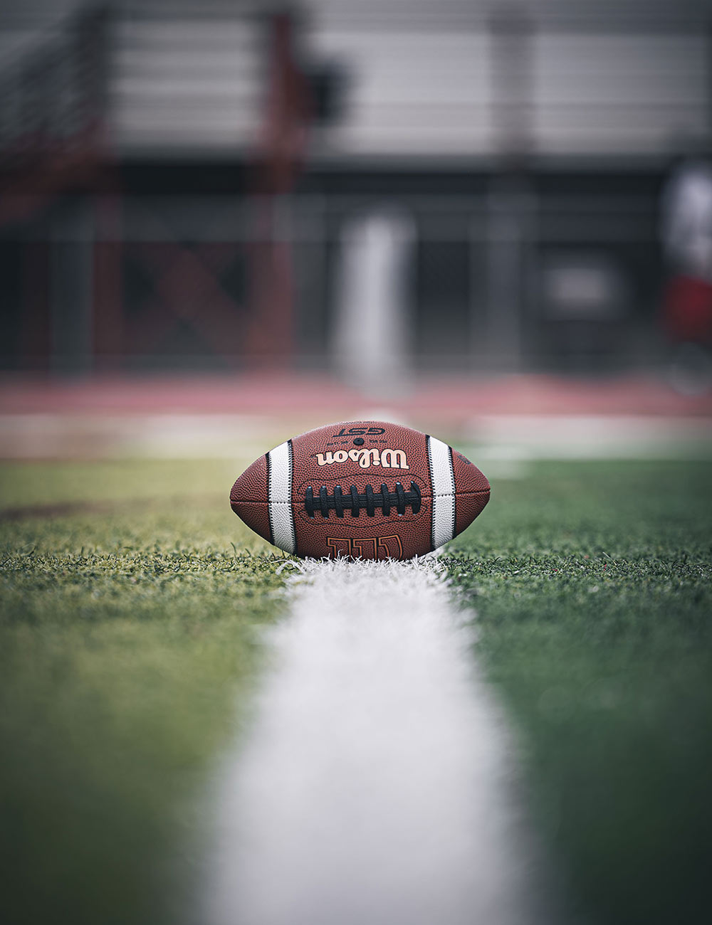 Football resting on the yard line of a stadium field, First Round Management football management division